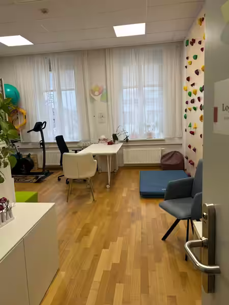 Physiotherapie Wolkersdorf – Therapieraum Eingang mit Besprechungstisch und Kletterwand